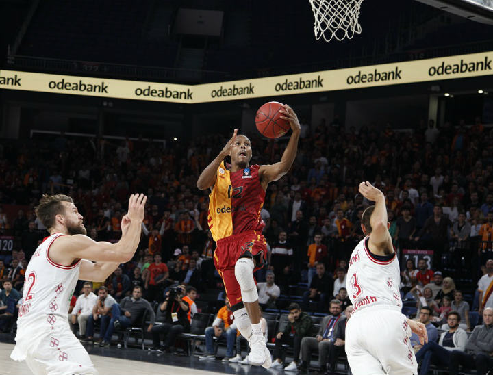basketball player in red and yellow jersey finishing at basket with layup