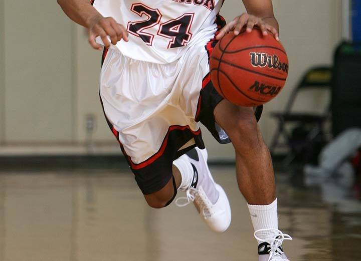 player in white and black jersey dribbling a basketball