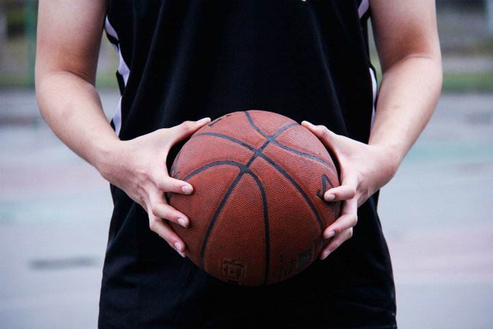 player in black jersey and shorts holding basketball